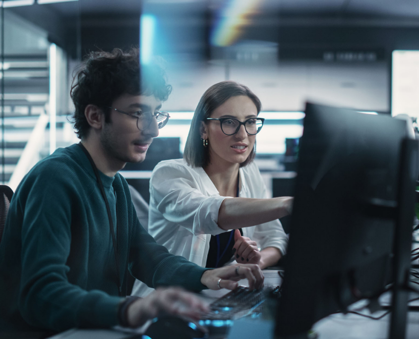 Two tech workers on a computer
